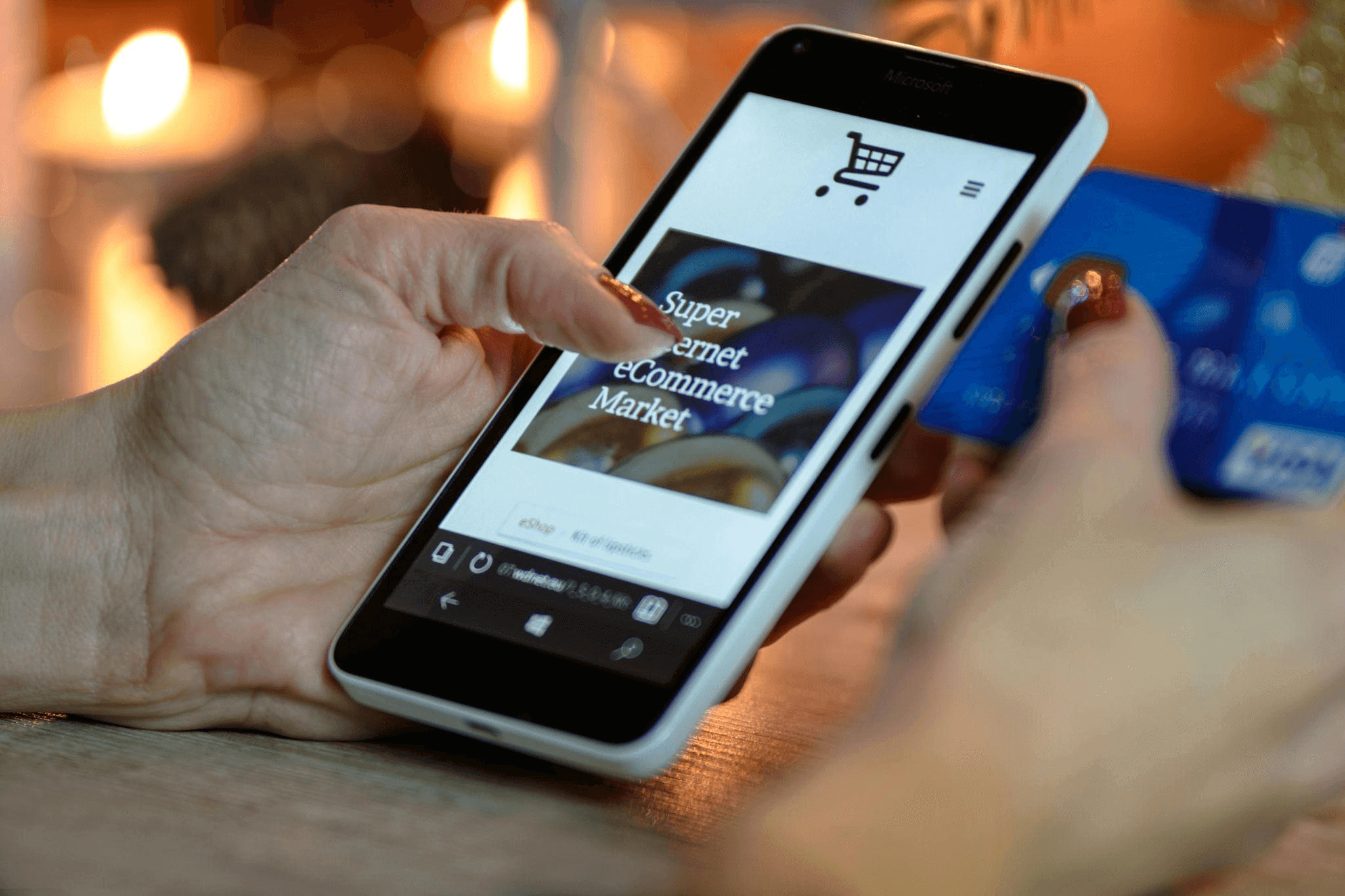 Person using a smartphone and holding a credit card, symbolizing online transactions in an ecommerce business.