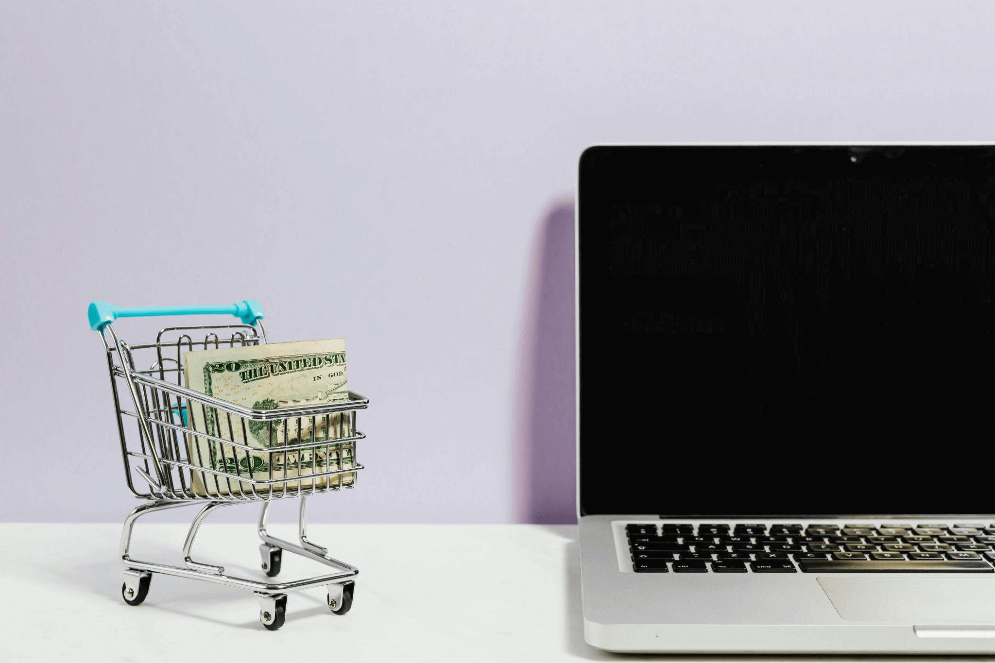 Shopping cart next to a laptop, representing the digital shopping experience in an ecommerce business.