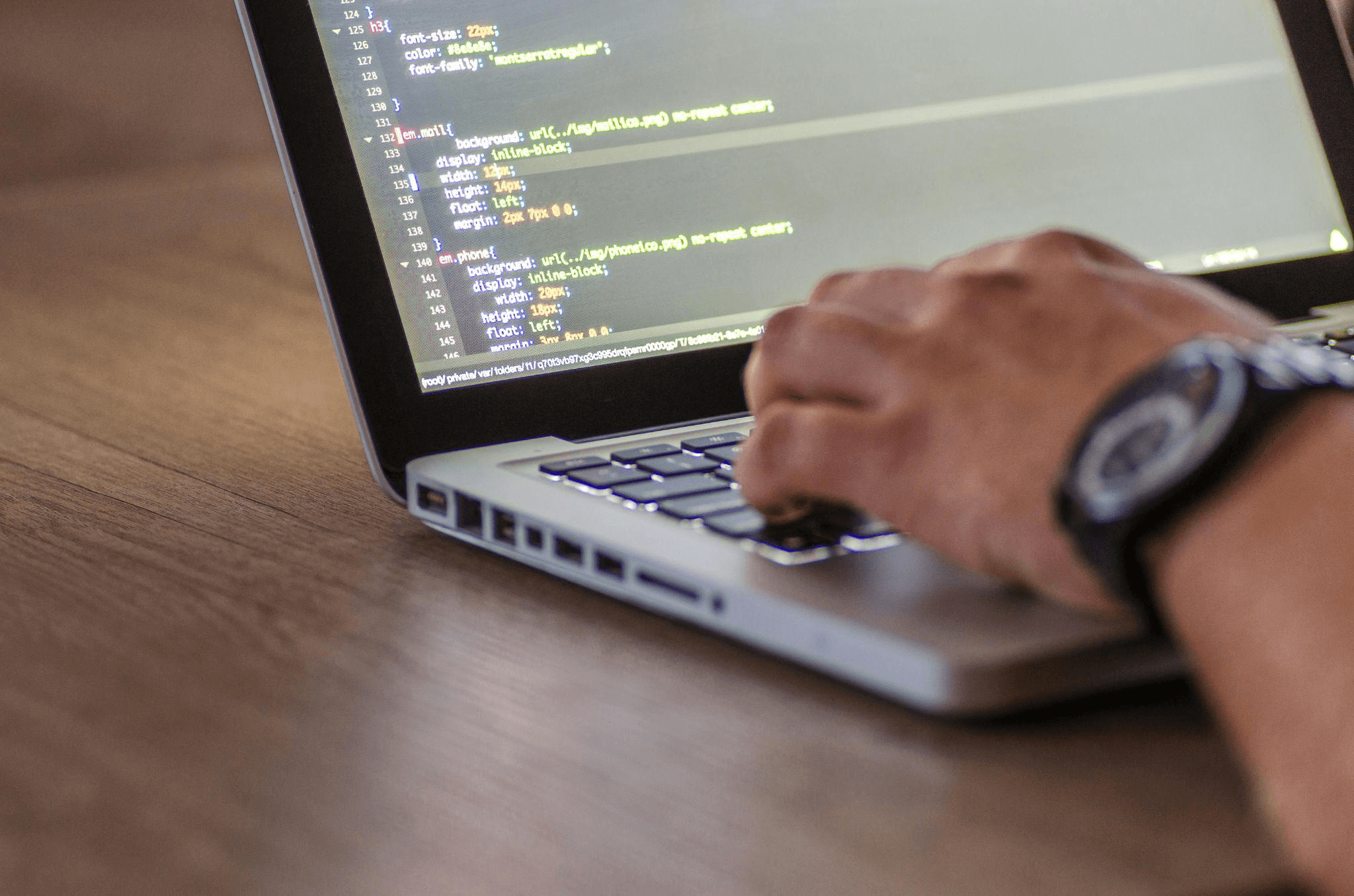 A developer typing code on a laptop, focused on optimizing app performance. The screen displays lines of code, highlighting the backend work involved in improving app loading times.