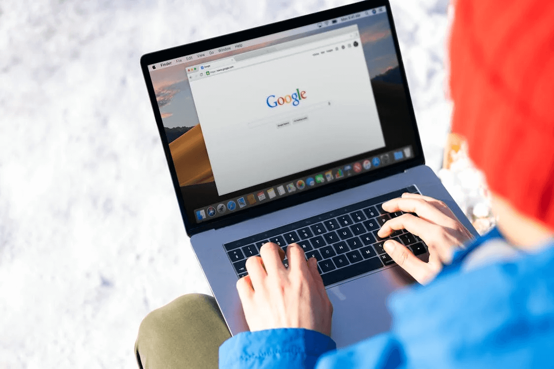  Person using a MacBook Pro with the Google website displayed on the screen, representing the importance of staying updated on Google Business Profile optimization trends.