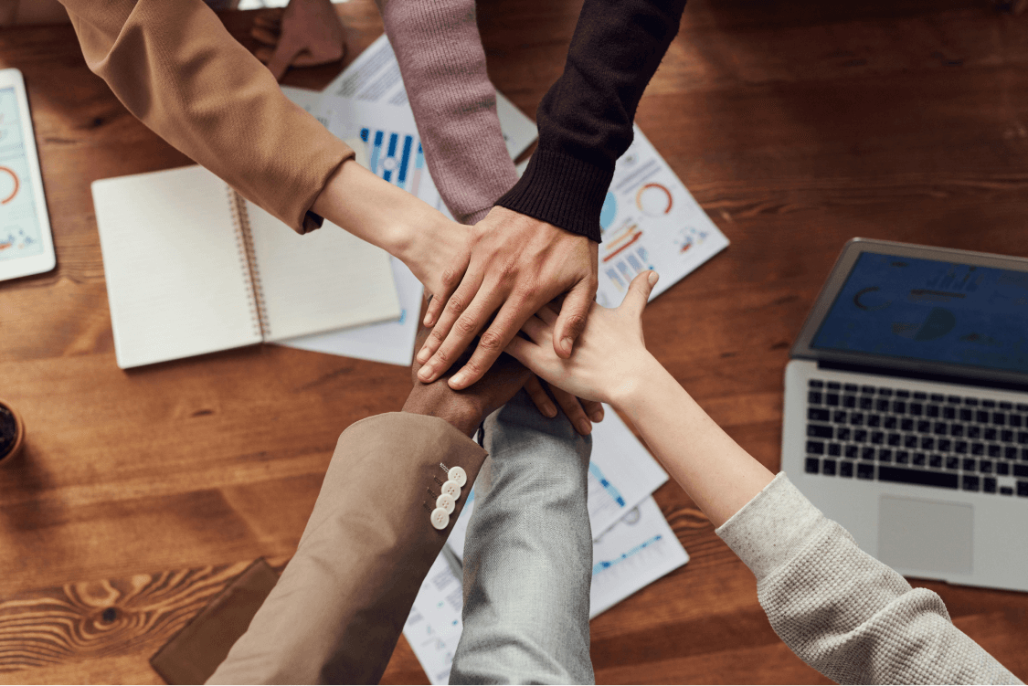 Group of people collaborating around a wooden table, symbolizing partnerships and community connections for effective Google Business Profile optimization.