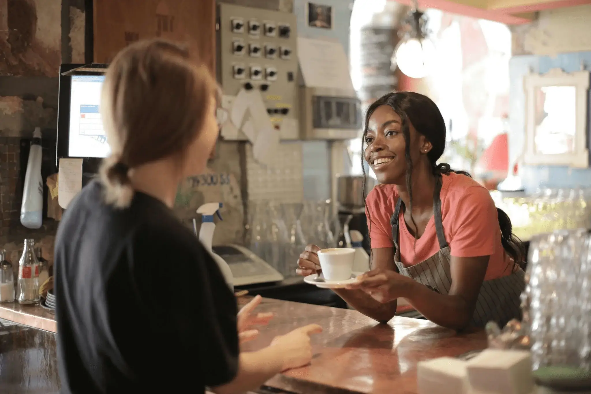 Barista engaging in conversational marketing by serving coffee with a smile, highlighting a personalized customer experience.