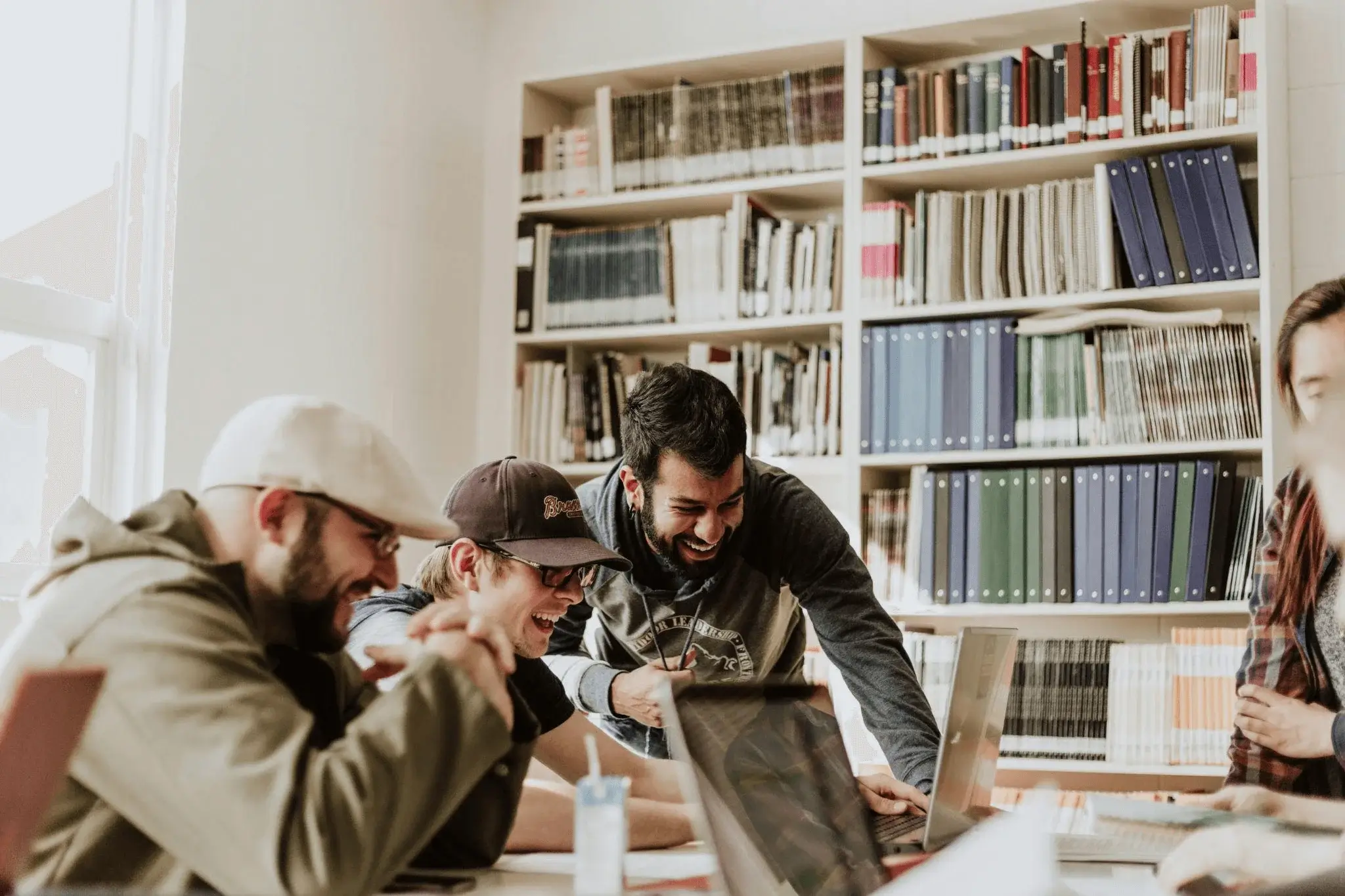 Three men building community through conversational marketing, laughing and engaging around a laptop.