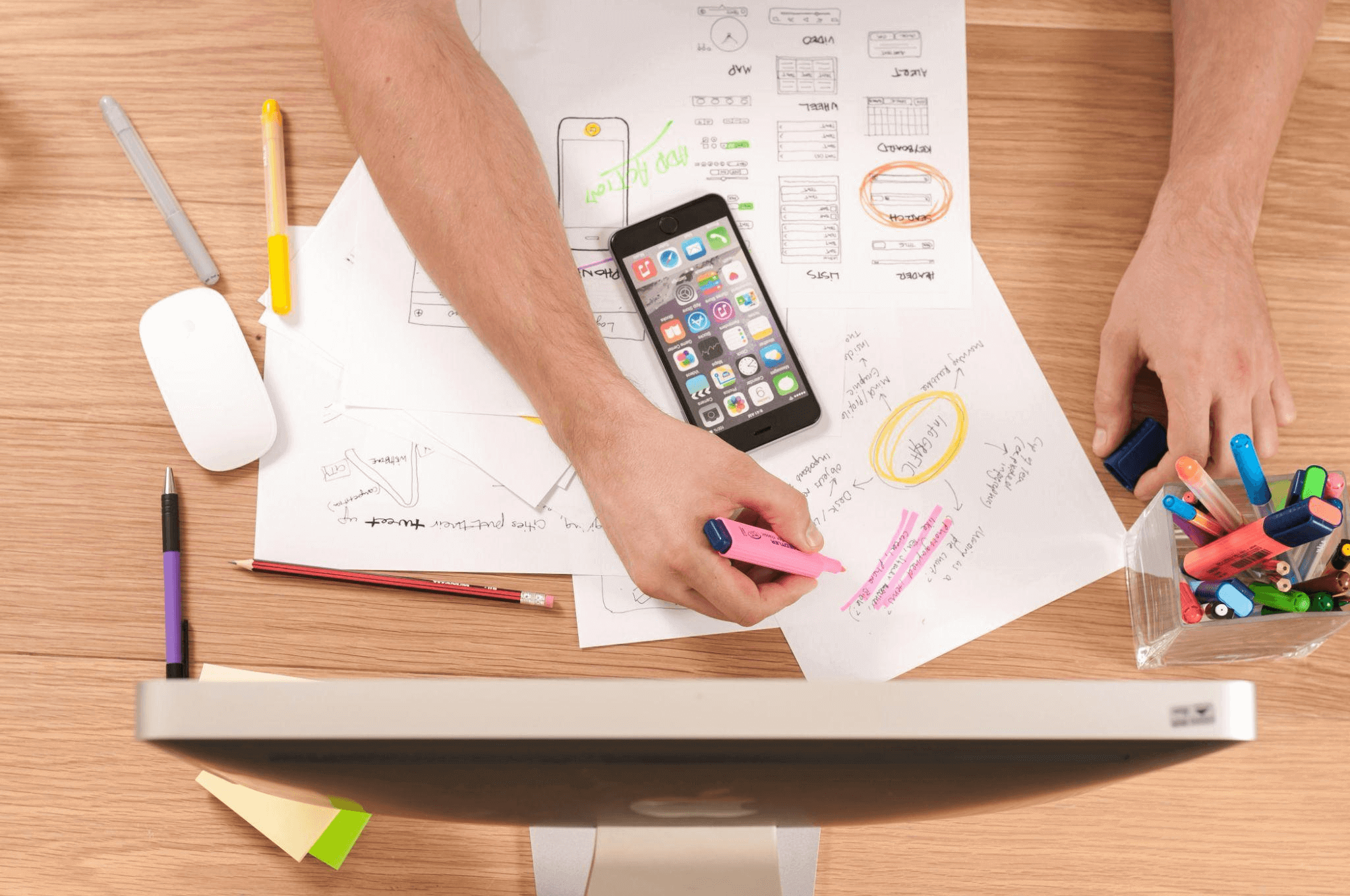Person writing notes on white paper while planning a web design project for a web design agency.