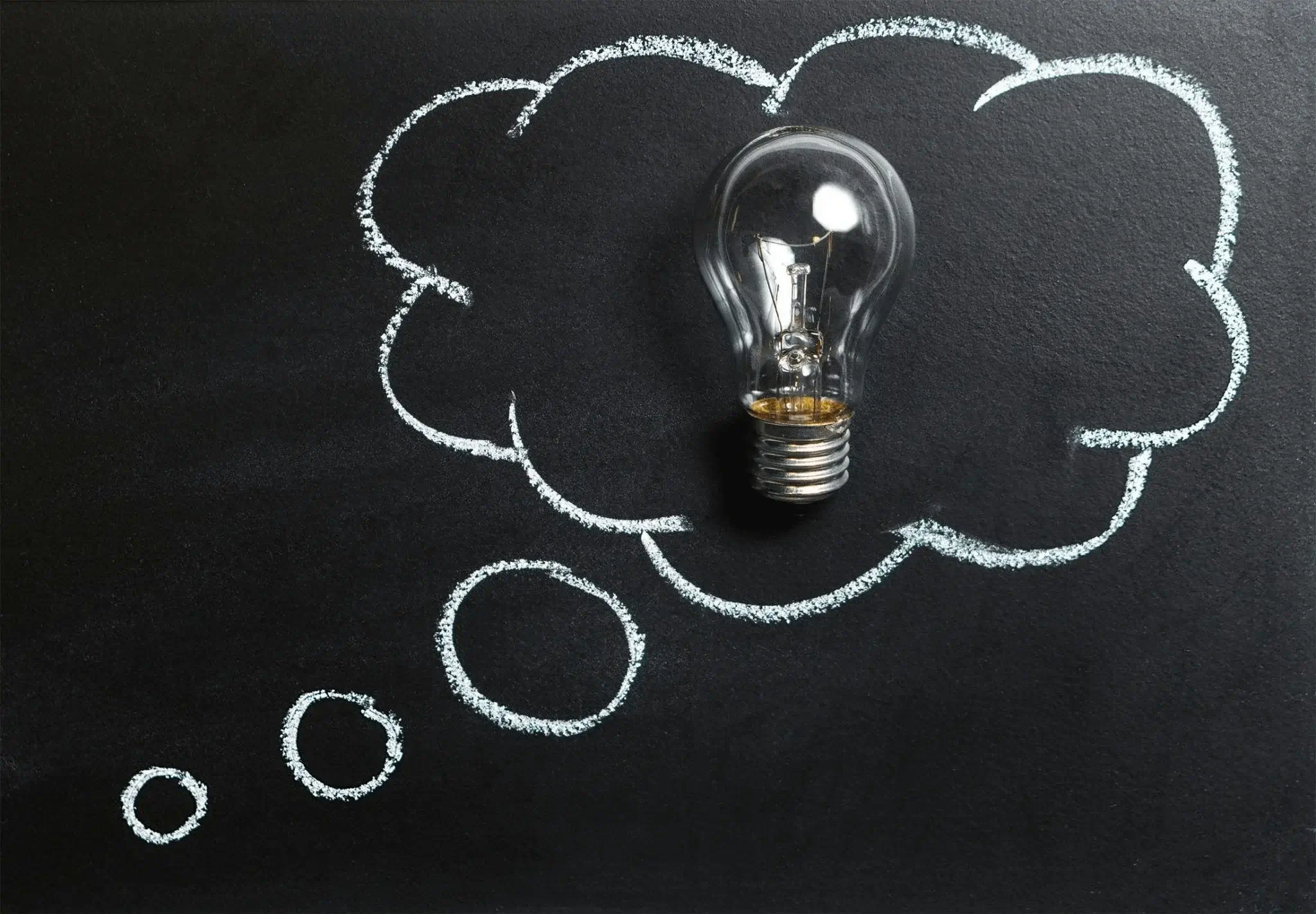 Bright light bulb on a chalkboard, symbolizing fresh ideas for content marketing tips for startups.