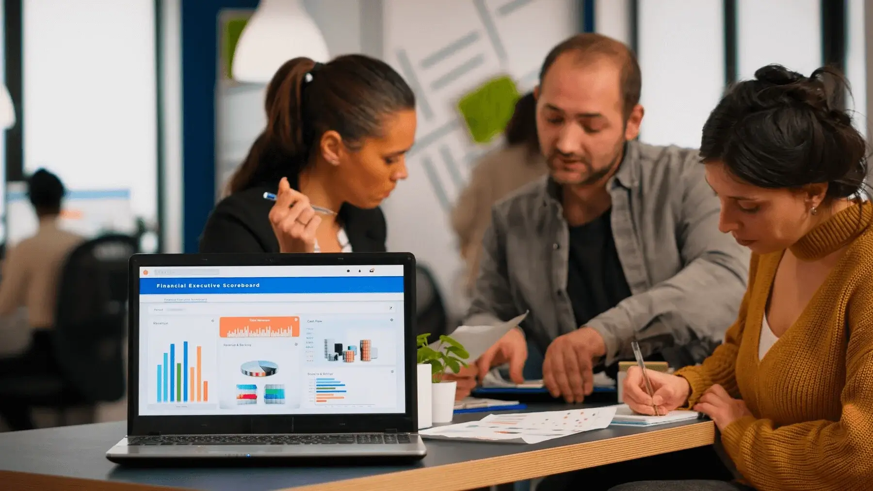 A team of professionals collaborating around a table with financial charts and graphs, while a laptop screen displays a financial executive dashboard, illustrating data-driven strategies relevant to SEO for financial services.
